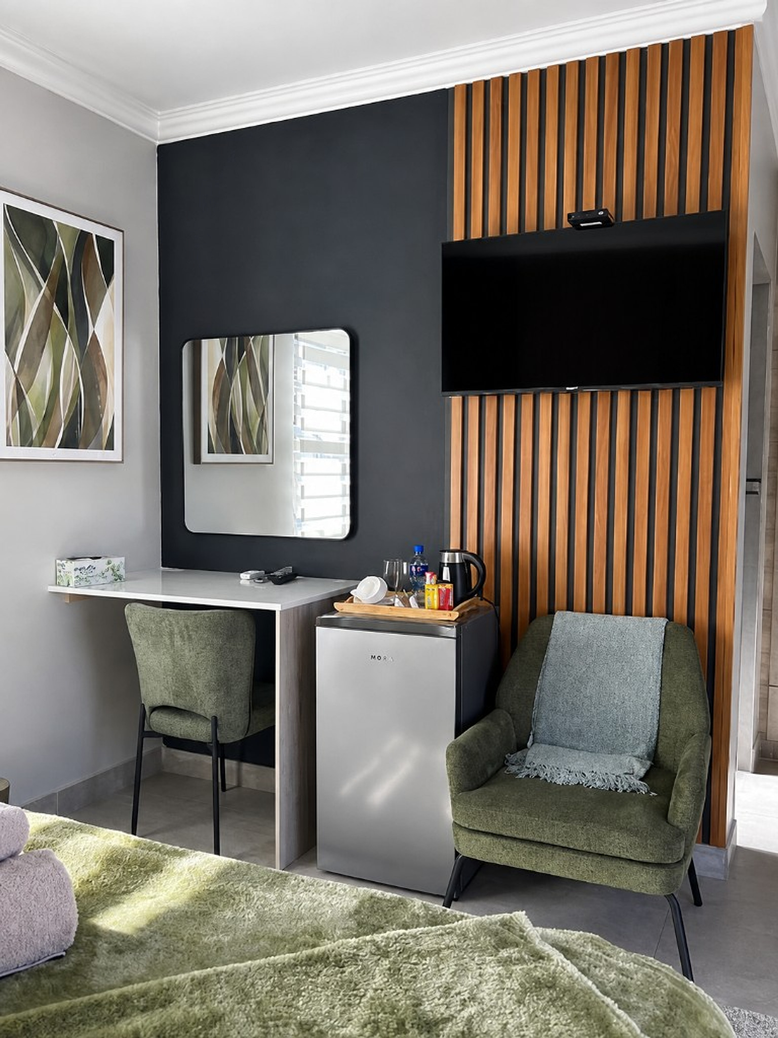 Sitting corner with olive chairs, TV wall, and minibar