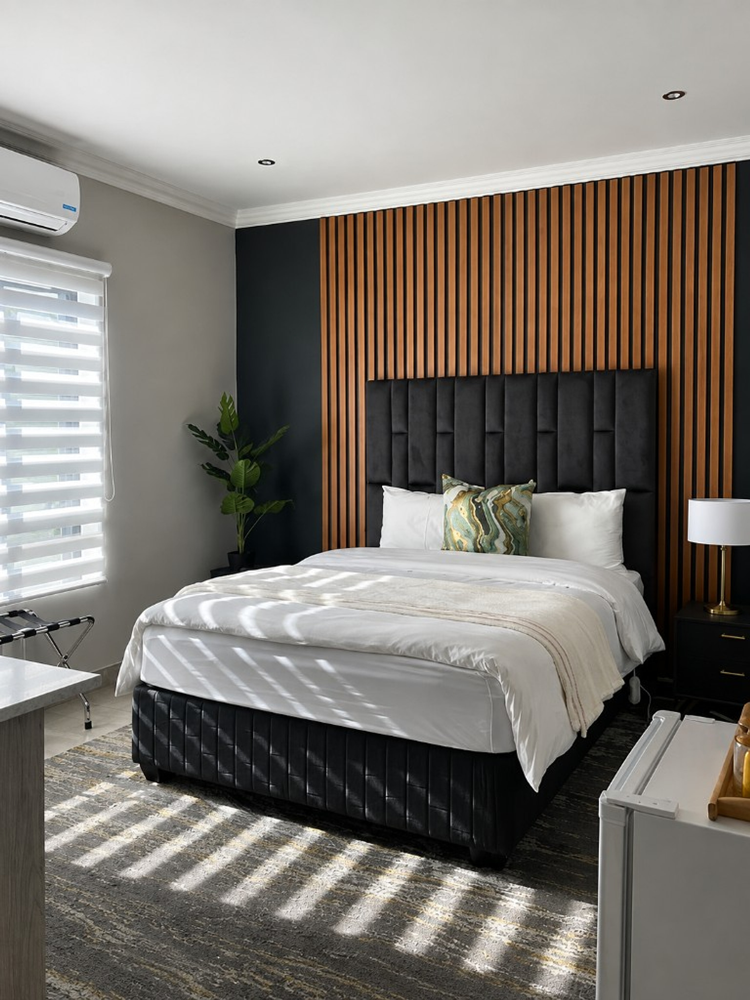 Sunlit bedroom with black headboard and wood feature wall