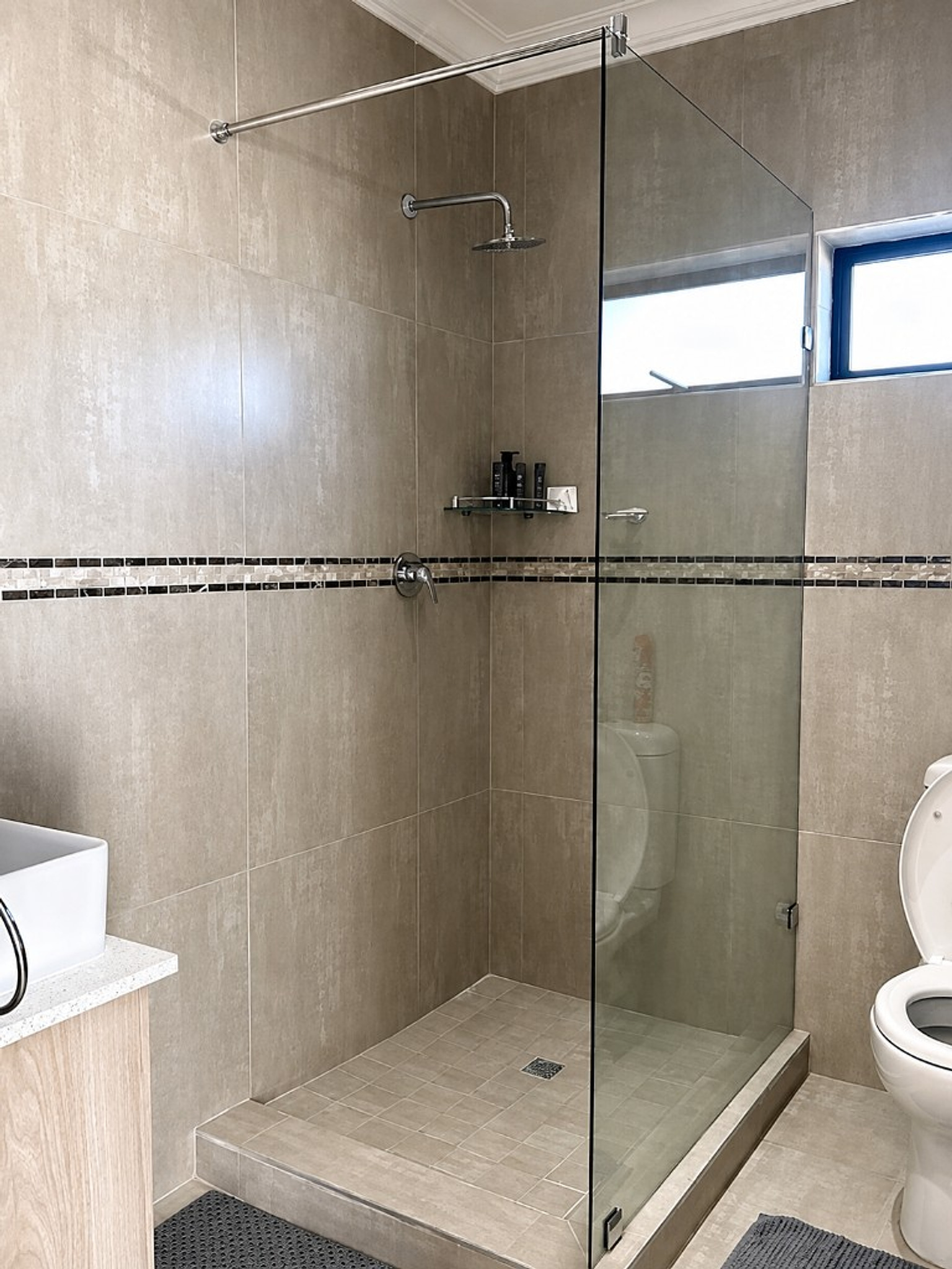 Walk-in glass shower with mosaic tile detail